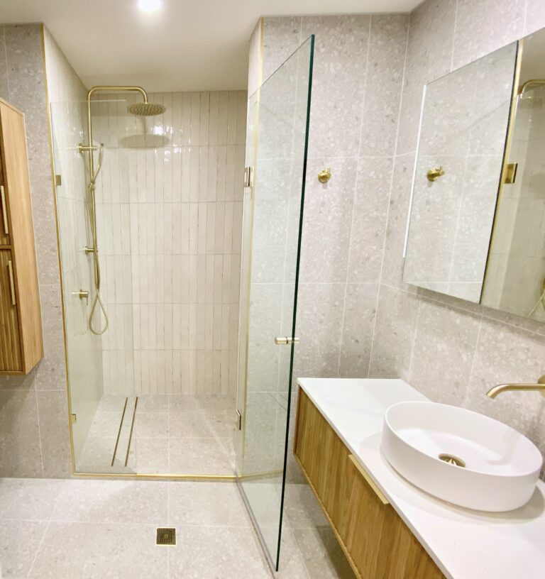 Completed ensuite bathroom renovation, shower cubicle with brushed gold fixtures and beige tiling
