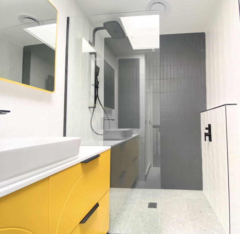 newly renovated bathroom with shower, yellow vanity and black fixtures